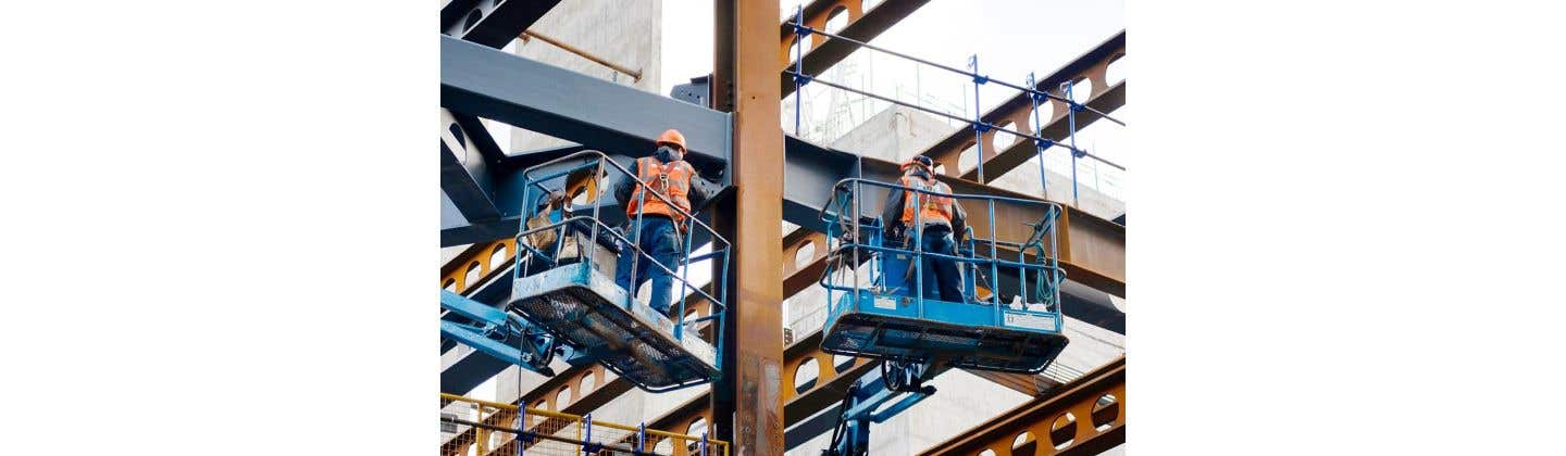 Two workers standing on elevated platforms with Fall Protection gear