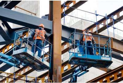 Two workers standing on elevated platforms with Fall Protection gear