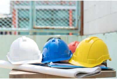 White, blue, and yellow construction hard hats resting on a table