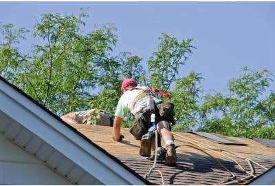 Worker on a roof with Fall Protection harness and other safety gear