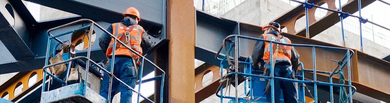 Two workers standing on elevated platforms with Fall Protection gear