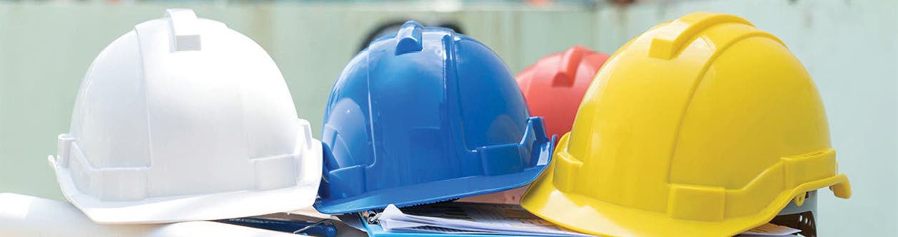 White, blue, and yellow construction hard hats resting on a table
